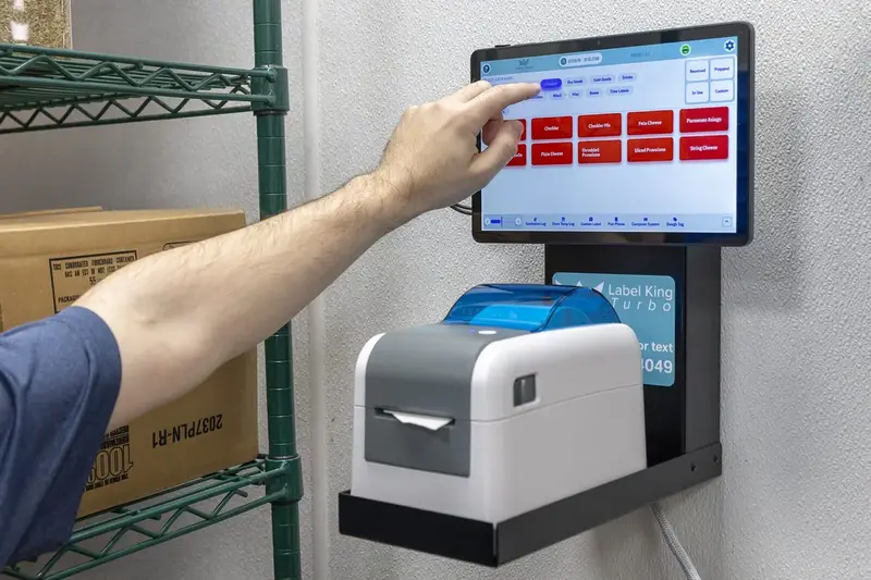 Wall-mounted Label King label printer and tablet on a kitchen prep rack